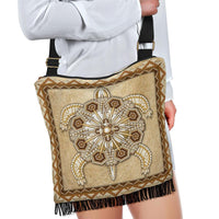 Tan boho crossbody purse with beadwork center emblem, fringe bottom, black shoulder strap