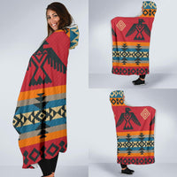 Red Native-style hooded blanket worn like a cape, featuring bold geometric artwork