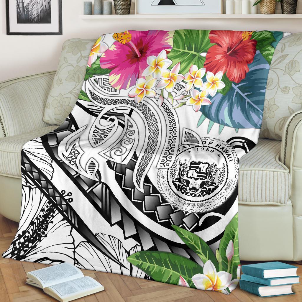 White Polynesian throw blanket with red and pink hibiscus, yellow plumeria, and tribal print