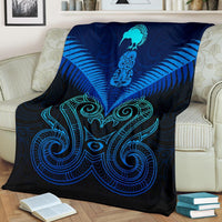 Blue blanket with teal and dark pattern of Maori manaia and swirls, covering sofa