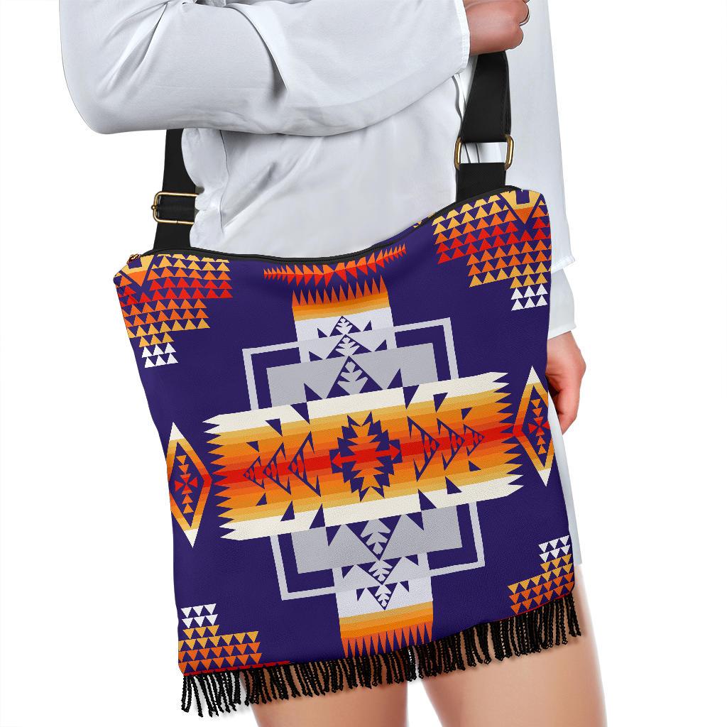 Purple patterned crossbody bag held by strap, gold buckle and fringe hem