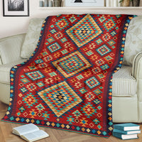 Geometric throw blanket draped on couch, red teal and green diamonds with navy edging