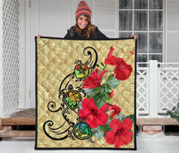 Beige premium quilt laid flat with black curvy turtle design and bright red hibiscus