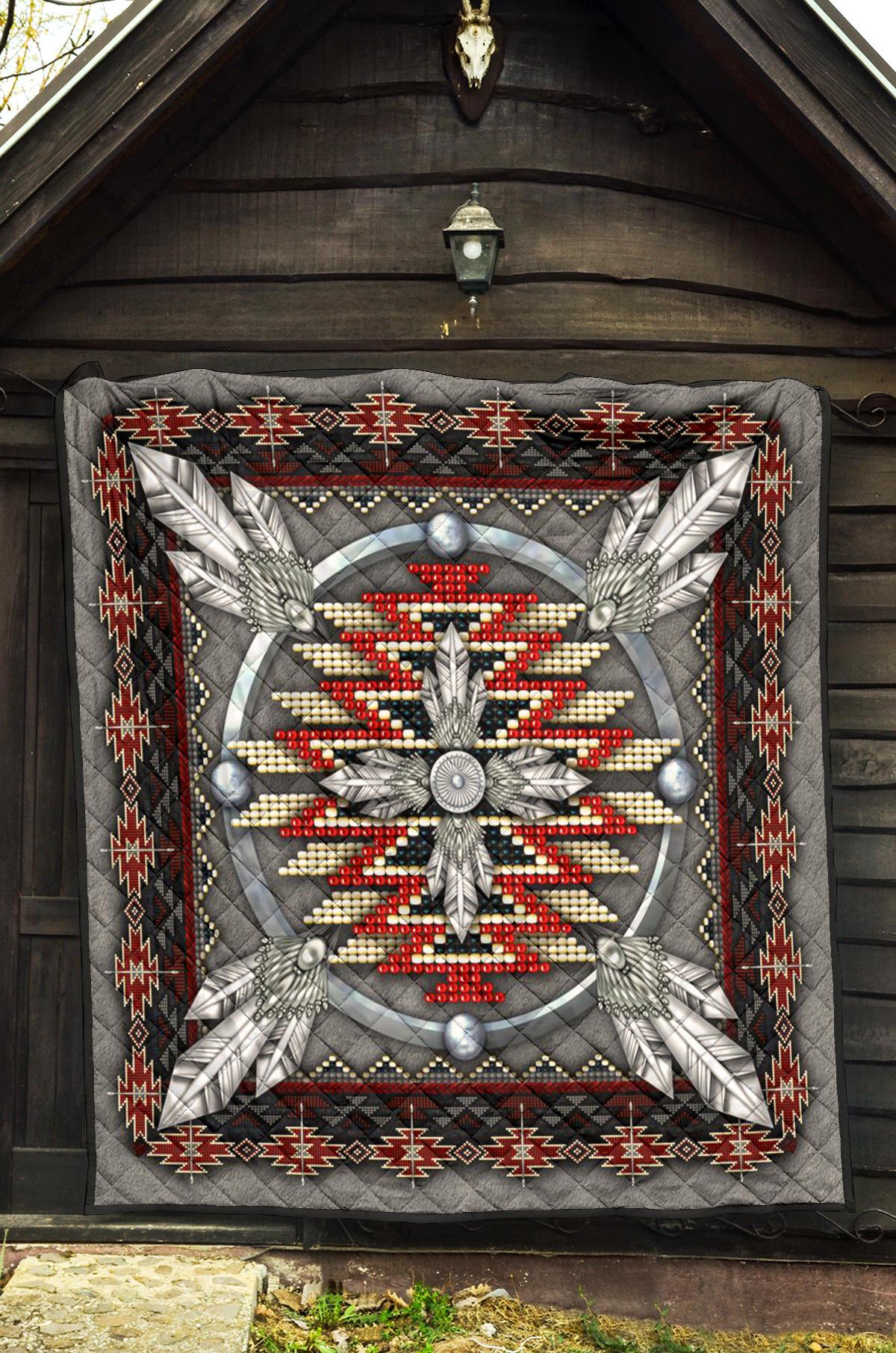 Grey quilt with ornate feather-and-bead medallion and red/white zigzag border.