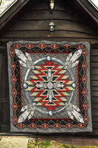 Grey quilt with ornate feather-and-bead medallion and red/white zigzag border.