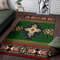Green rug with central sunburst motif, surrounding shapes, and patterned border trim
