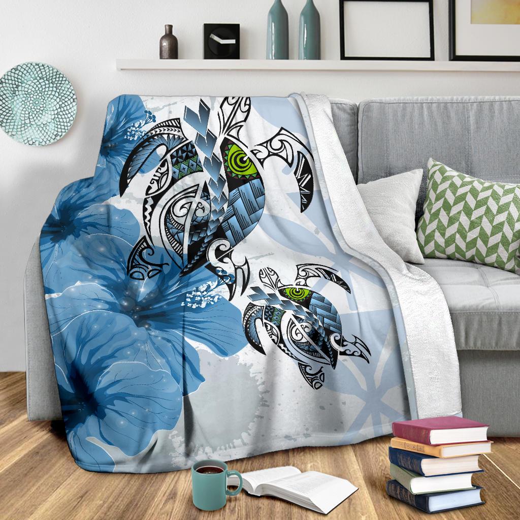 Blue Polynesian turtle and hibiscus blanket with green-eyed turtles, draped on sofa