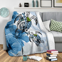 Blue Polynesian turtle and hibiscus blanket with green-eyed turtles, draped on sofa