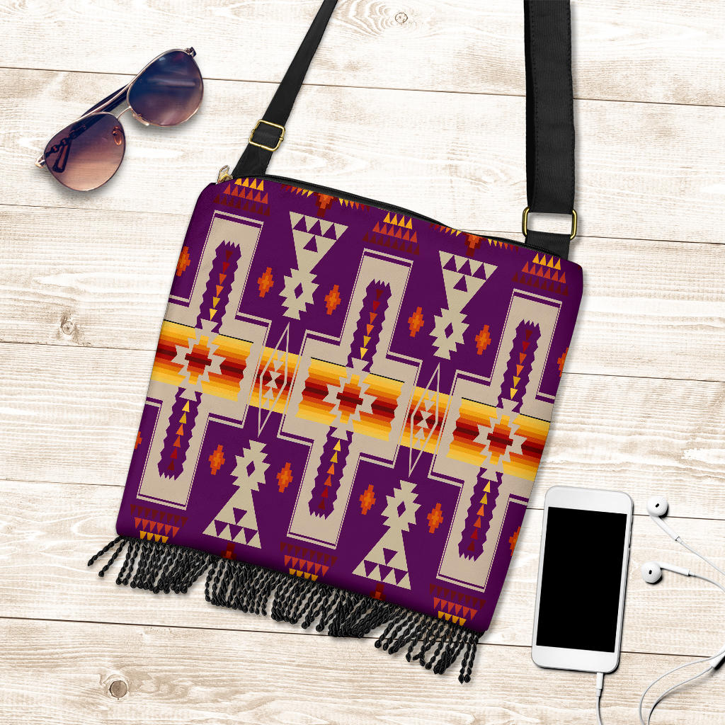 Purple patterned crossbody handbag with fringed edge and adjustable black strap.