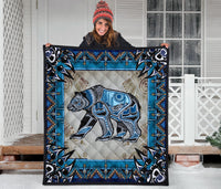 Square quilt top view: stylized bear in blue and black on light tan patchwork background