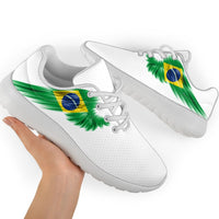 White sneakers with Brazil flag wing graphic and green laces, hand holding pair