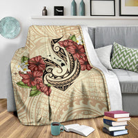 Beige blanket with large fish hook emblem and red hibiscus blooms over tribal print