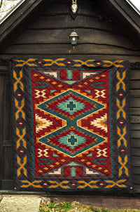 Geometric diamond Native American quilt in red, teal, and yellow with dark blue border