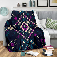 Navy tribal geometry blanket draped over sofa with purple, teal and cream accents