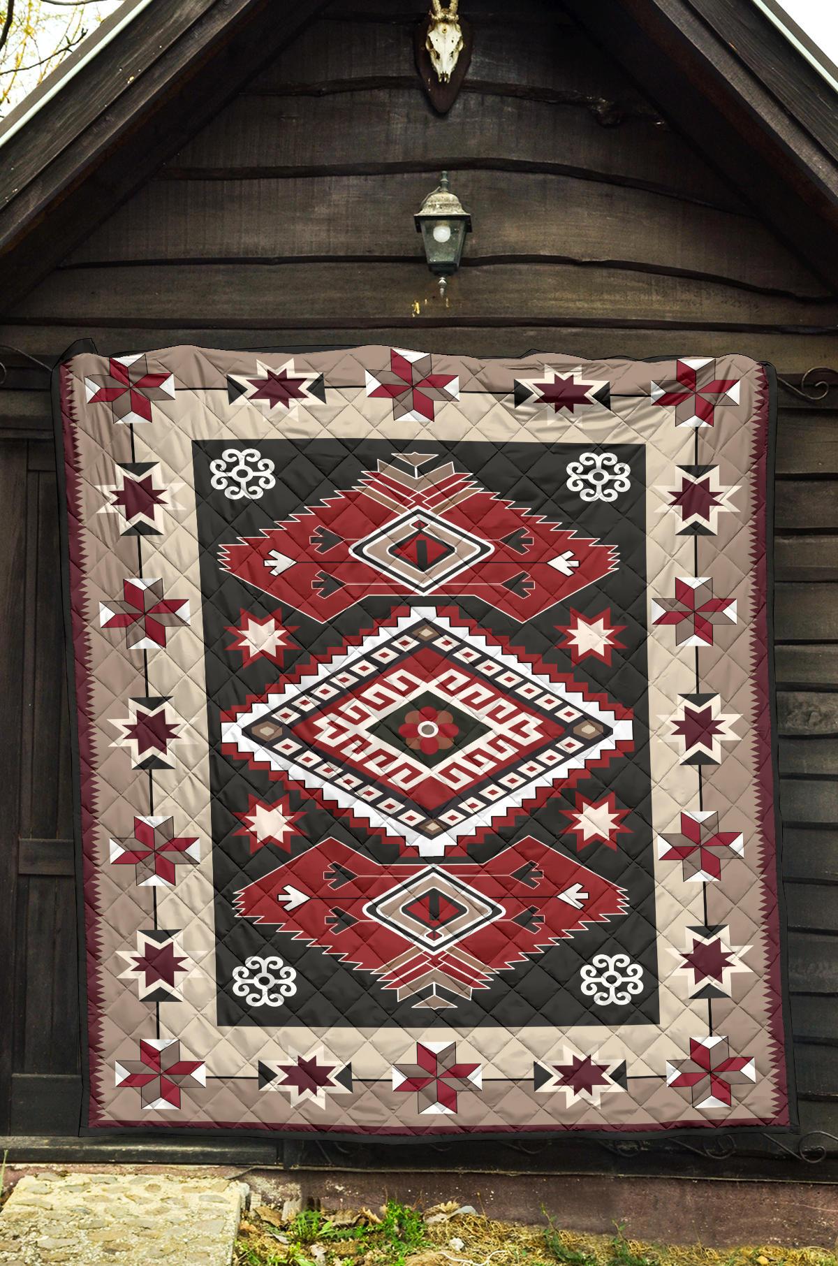 Quilt draped on wall featuring red and gray geometric squares, diamonds, and stars.