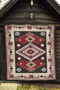 Quilt draped on wall featuring red and gray geometric squares, diamonds, and stars.