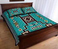 Teal quilt and two pillowcases featuring Native-inspired patterns, zigzag bands, and floral motifs