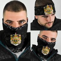 Black paisley neck gaiter with colorful coat-of-arms emblem, worn on face