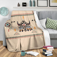 Beige Native bison blanket with multicolor geometric icons, shown on bed with folded edge