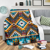 Multicolor geometric blanket draped on couch, navy and teal patterns with orange and red details