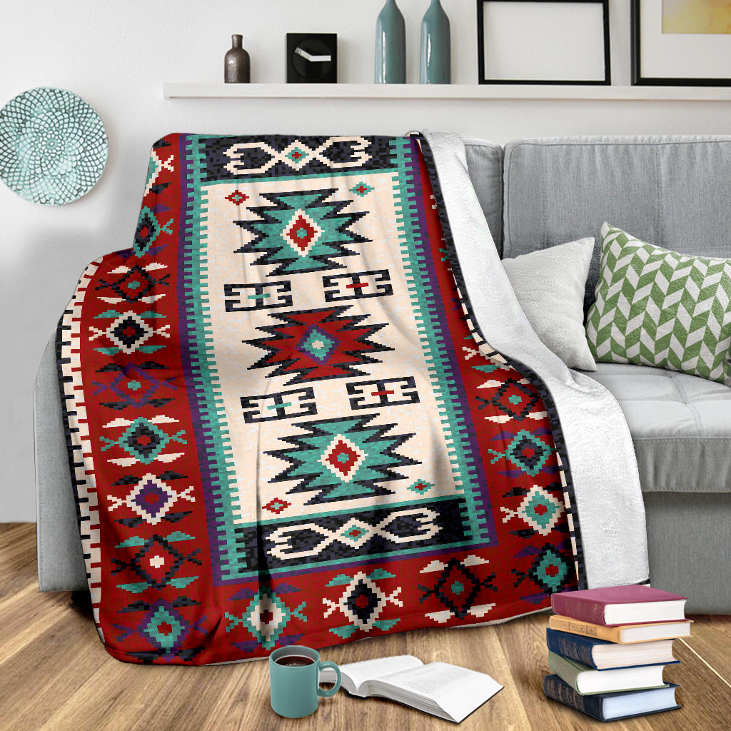 Red geometric blanket with cream panel and teal border over a gray couch