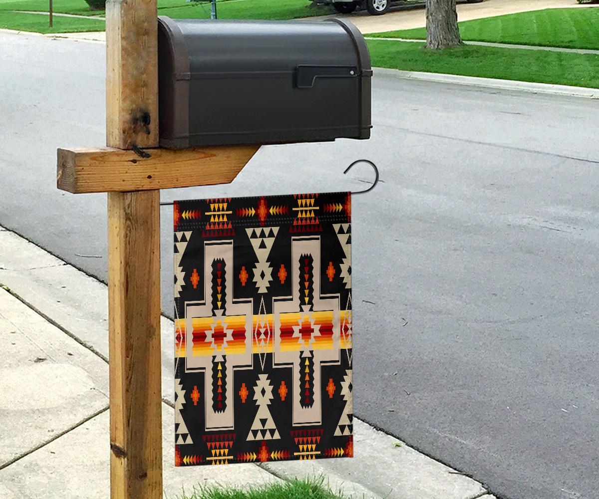 Black tribal design flag hanging from a wooden post, multicolor crosses and arrow shapes