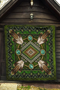Green Native American mandala quilt displayed on a wall, feather and bead detail with turquoise rings.