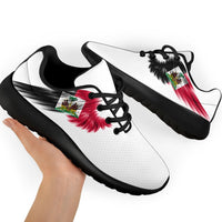 White sneakers with Haiti flag wing graphic; black outsole and black laces, angled view