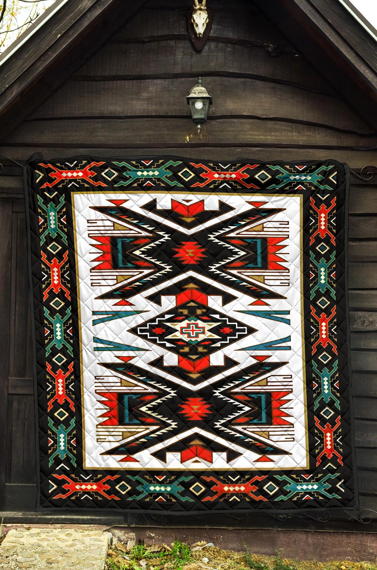 Geometric Native American-style quilt hanging on porch with black border and multicolor pattern