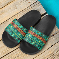 Pair of black slide sandals with green patterned straps and wide open toe