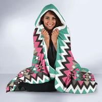 Teal hooded blanket with white-lined hood, bold zigzag geometric design and pink highlights