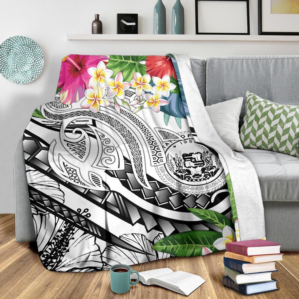 White Polynesian blanket draped over a couch with plumeria flowers and black-and-white motifs