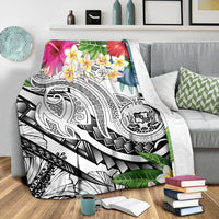 White Polynesian blanket draped over a couch with plumeria flowers and black-and-white motifs