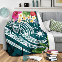 Turquoise summer blanket draped over couch arm, hibiscus and plumeria flowers with white tribal design