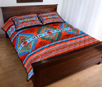 Colorful native-inspired quilt with red base, zigzag trim, and two square pillow shams