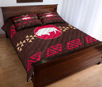 Brown quilt with pink bison oval centerpiece and red triangle motifs, two decorative shams