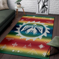 Colorful rainbow area rug featuring blue feather emblem with geometric star and arrow motifs