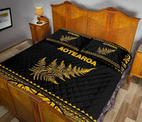 Black quilt bed set with yellow Aotearoa text, fern center and ornate stripe edging