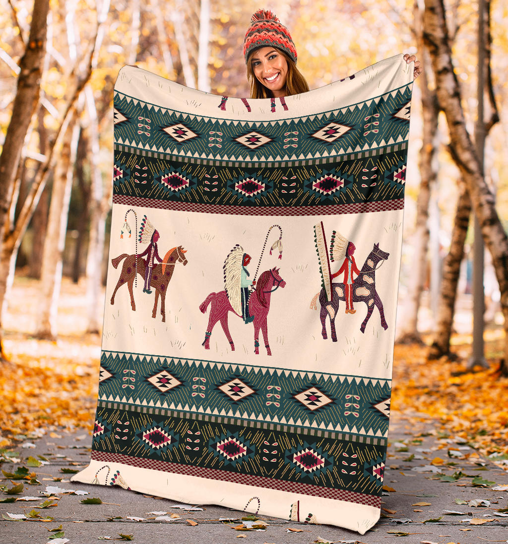 Chief horse blanket held outdoors, teal geometric band and horse rider panel