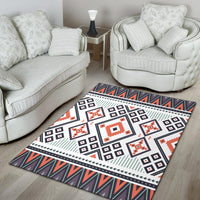 Geometric tribal area rug in white with orange-red motifs, navy squares, and patterned border