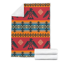 Red geometric blanket with orange and teal stripes, dark green motifs; rolled white towels