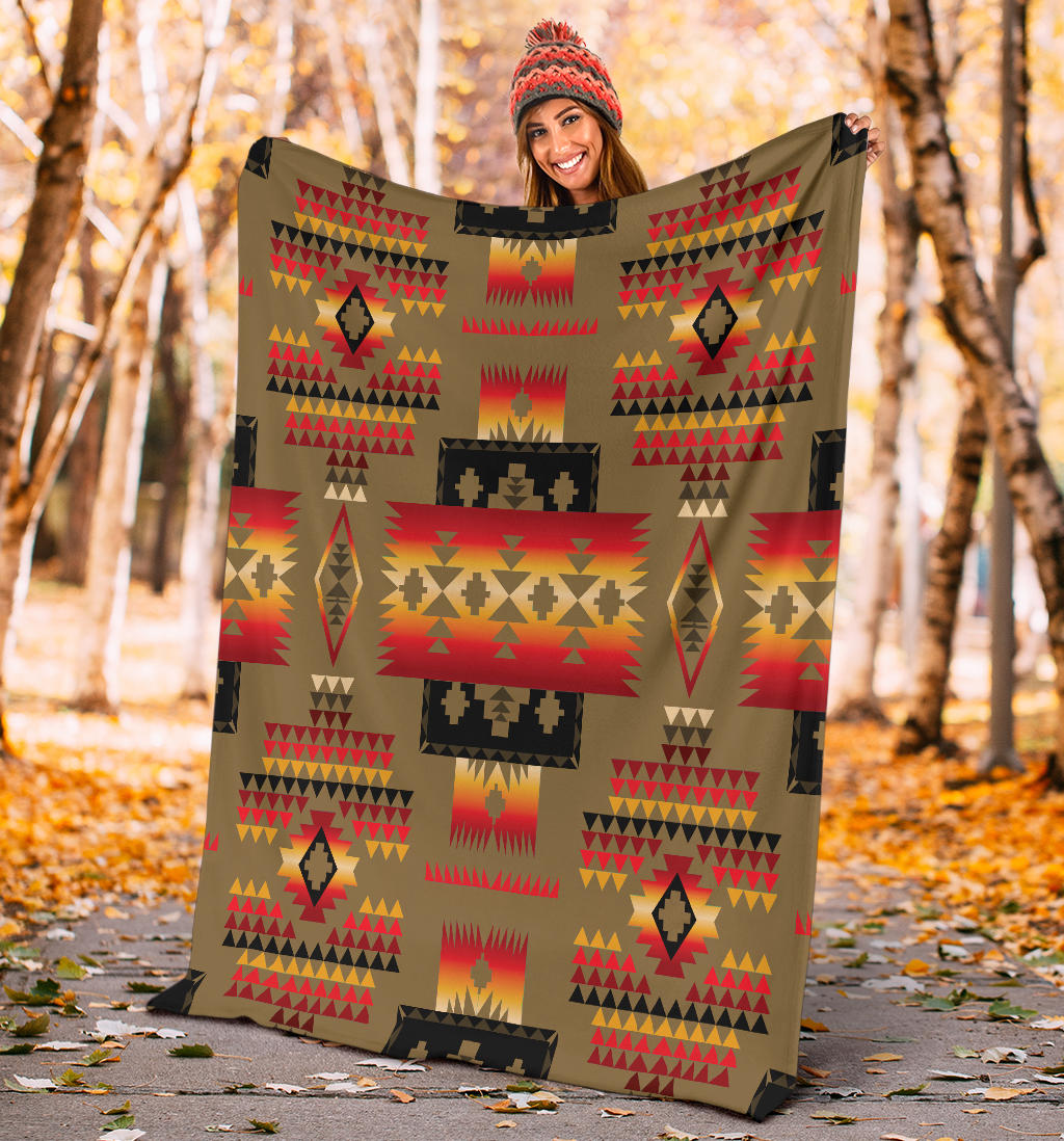Dark brown blanket with bold tribal geometric print in red, yellow, and black, held up