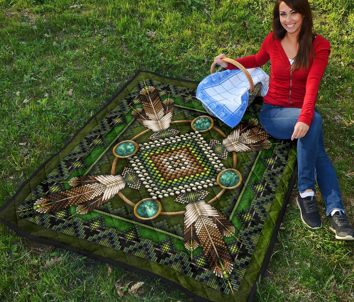 Green Native American mandala quilt draped on grass, turquoise circles and beaded sunburst center.