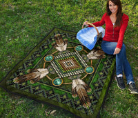 Green Native American mandala quilt draped on grass, turquoise circles and beaded sunburst center.