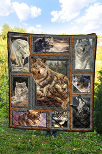 Multicolor wolf quilt hanging on grass, framed wolf portraits with orange-trimmed border