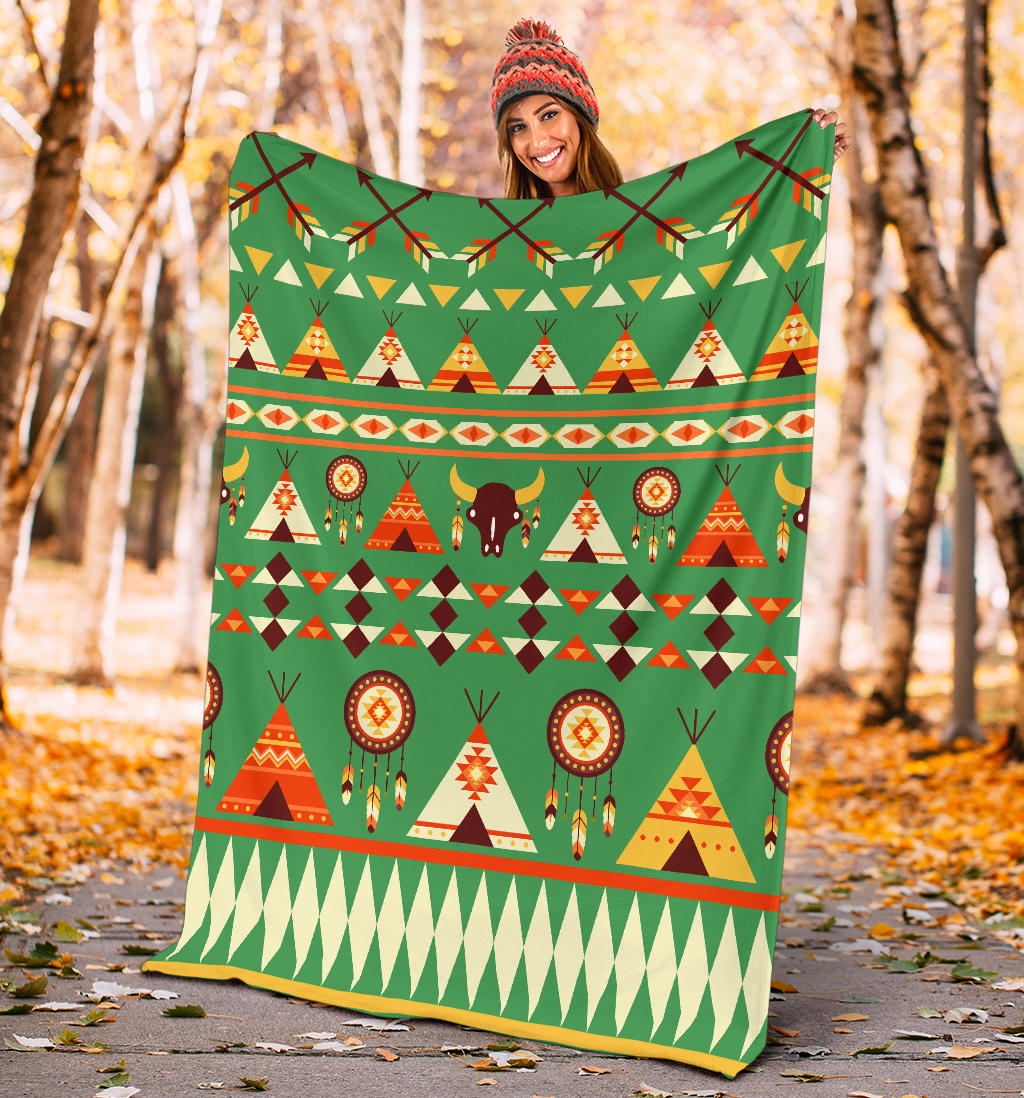 Green outdoor blanket held up, featuring tents, bison, and dreamcatcher circle pattern