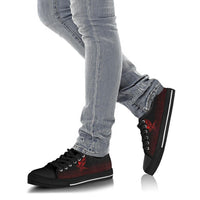 Black low-top sneakers with red rune graphic worn with light blue jeans