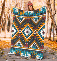 Aztec geometric blanket held up outdoors, navy, teal, orange, red, and white tribal motifs