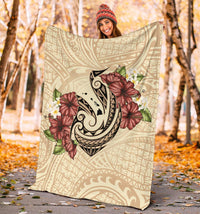 Beige Polynesian blanket outdoors showing fish hook motif and red hibiscus plumeria flowers