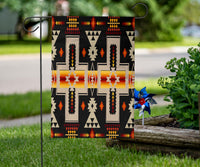Black geometric motif flag with bright multicolor cross shapes, displayed on lawn with stakes